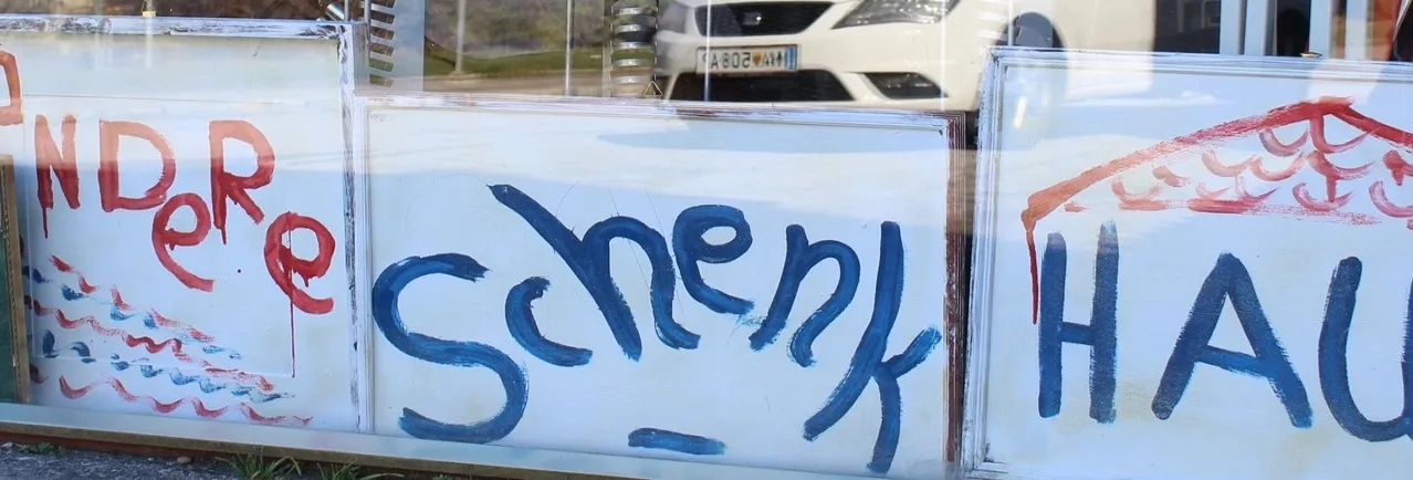 Eine Reihe von drei Schildern mit Graffiti darauf. Das linke Schild hat 'DAS' in Blau, das mittlere Schild hat 'Schenkel' in Blau und das rechte Schild hat 'HAUS' in Blau.