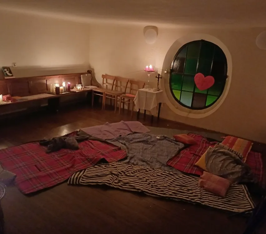 Ein gemütliches Zimmer mit einem runden Fenster, Holzbänken und einem Tisch mit Kerzen.