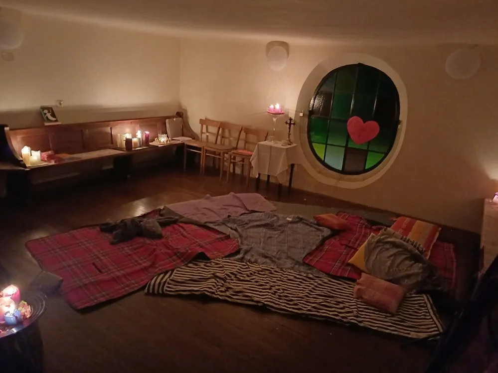 Ein gemütliches Zimmer mit einem runden Fenster, Holzbänken und einem Tisch mit Kerzen.