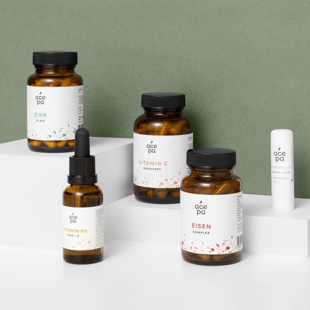 Fünf Flaschen Acepa-Nahrungsergänzungsmittel werden angezeigt: Zink, Vitamin C, Vitamin D3, Eisen-Komplex und eine kleine weiße Tube. Jede Flasche hat einen schwarzen Deckel und ein weißes Etikett mit dem Acepa-Logo und Produktnamen.