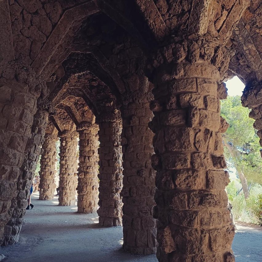 Ein steinerner Bogen mit Säulen und gewölbten Decken. Eine Person läuft im Vordergrund.