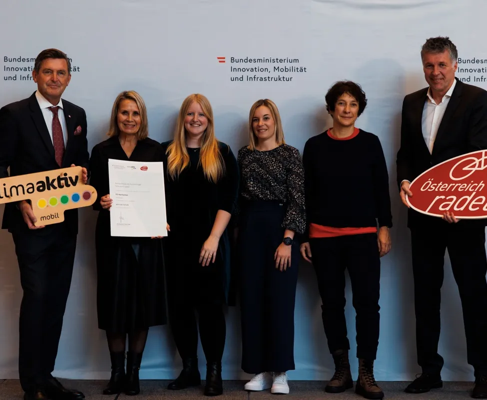 Fünf Personen posieren für ein Foto vor einem weißen Hintergrund mit der Aufschrift 'Bundesministerium Innovation, Mobilität und Infrastruktur'. Sie halten Urkunden und ein Schild mit dem Wort 'aktiv'.