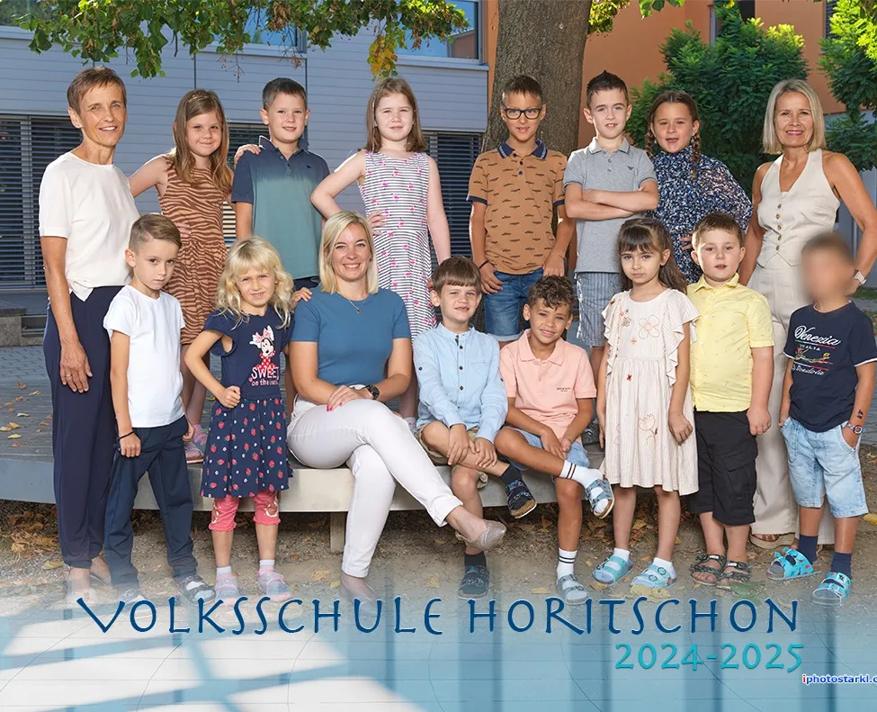 Eine Gruppe von Kindern und zwei Frauen posiert für ein Foto vor einem Gebäude, mit dem Text 'Volksschule Horitschon 2024-2025' unten.