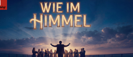 A musical performance on a stage with a man in the center, arms outstretched, under a dramatic sky with clouds and a spotlight effect.