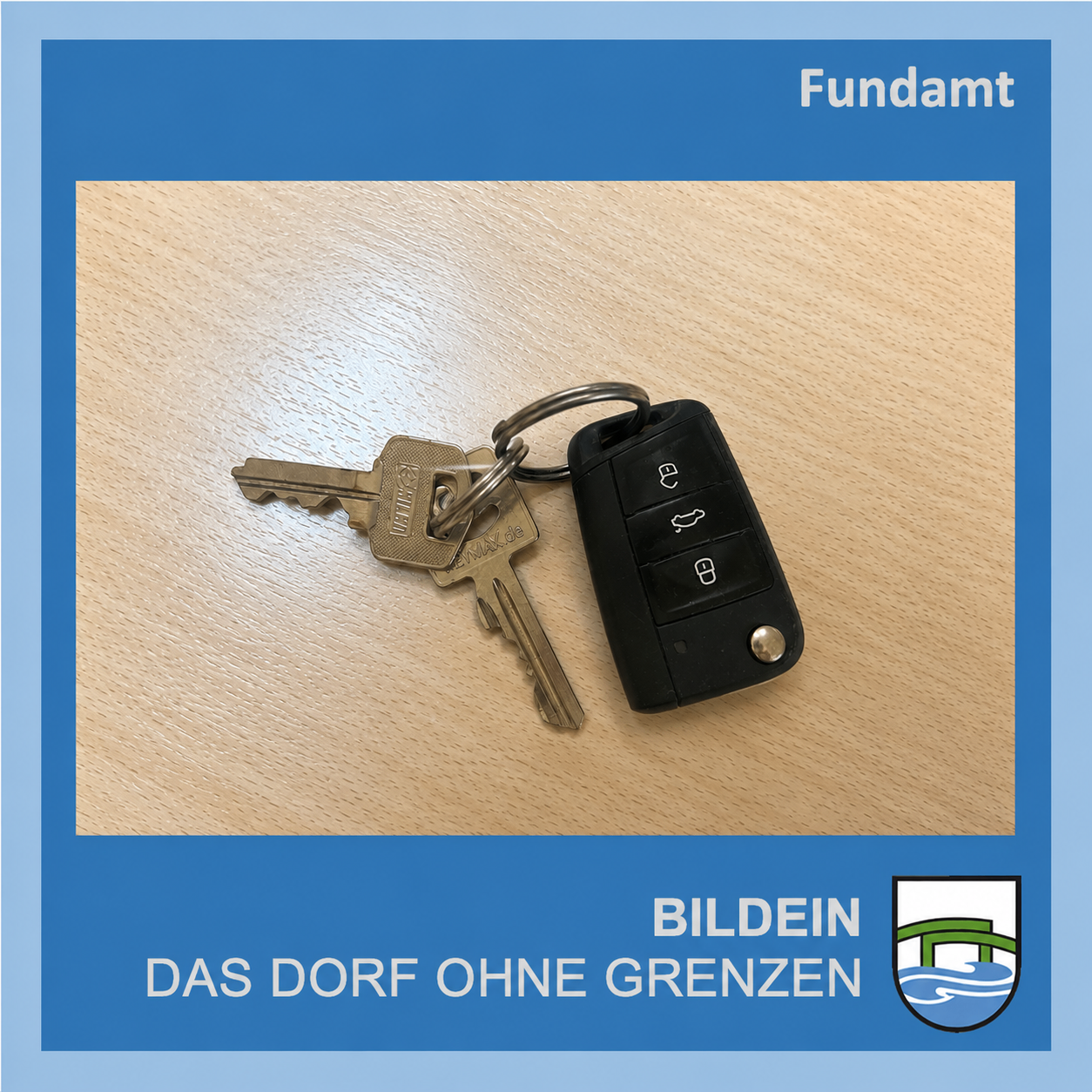 Ein Schlüsselbund mit einem Autoschlüssel und einem Hausschlüssel auf einer Holzoberfläche. Der Schlüsselbund ist schwarz mit einem silbernen Ring. Der Autoschlüssel hat Tasten zum Ver- und Entriegeln und für die Kofferraumöffnung. Der Hausschlüssel ist silbern.