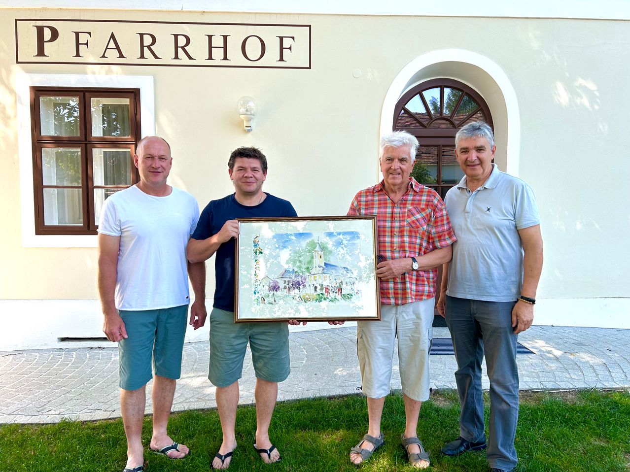 Four men stand in front of a building named Farrhof, holding a framed painting. The man on the left wears a white shirt and shorts. The man in the center wears a blue shirt and shorts. The man in the middle holds the painting. The man on the right wears a blue polo shirt and pants.