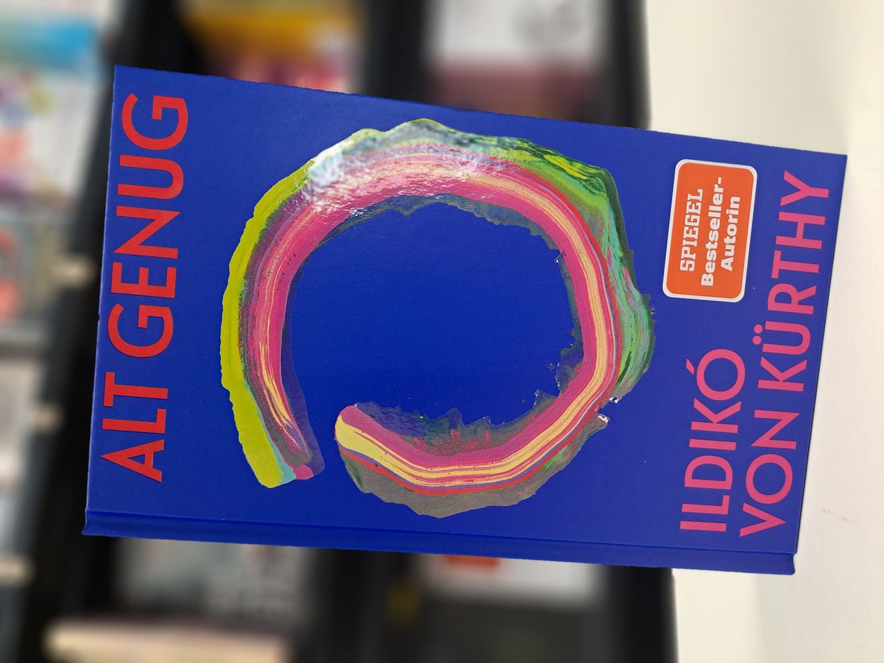 A book cover with blue background and colorful abstract design. The title 'ALT GENUG' is in red, and 'ILDIKO VON KUN' is in white on the right. A red sticker says 'SPIEGEL Bestseller Autorin'.