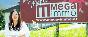 Eine Frau steht vor einem Werbeschild von Mega Immo mit einer lächelnden Frau darauf sitzend.