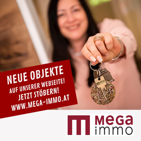 Eine lächelnde Frau hält einen Schlüssel, auf dem die Website www.mega-immo.at prominent angezeigt wird. Der Schlüssel ist gold und glitzert. Hinter ihr ist ein unscharfer Hintergrund.