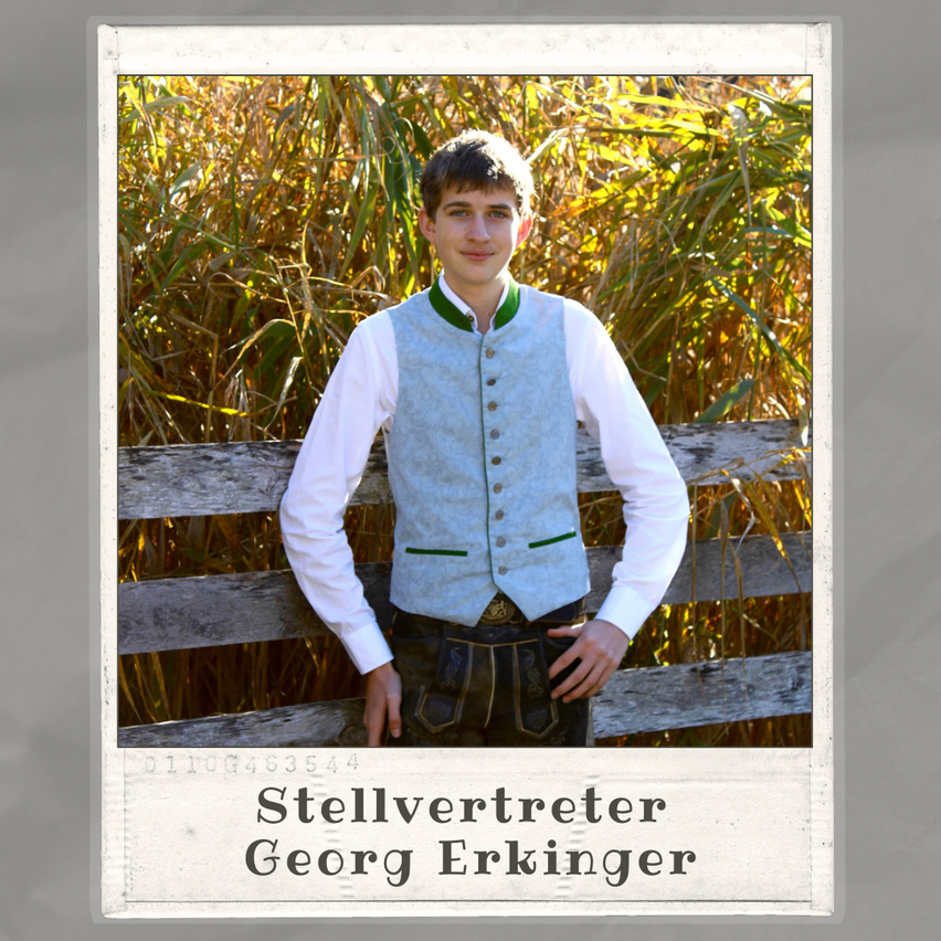 Ein junger Mann in einem hellblauen Westchen und traditioneller Hose steht vor einem Hintergrund aus hohem Gras. Das Foto enthält eine Bildunterschrift, die 'Stellvertreter Georg Erkinger' lautet.