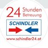 Ein rundes Aufkleber mit dem Text '24 Stunden Service SCHINDLER' und roten und blauen Pfeilen, die auf und vom Text zeigen. Darunter wird die Website 'www.schindler24.at' angezeigt.