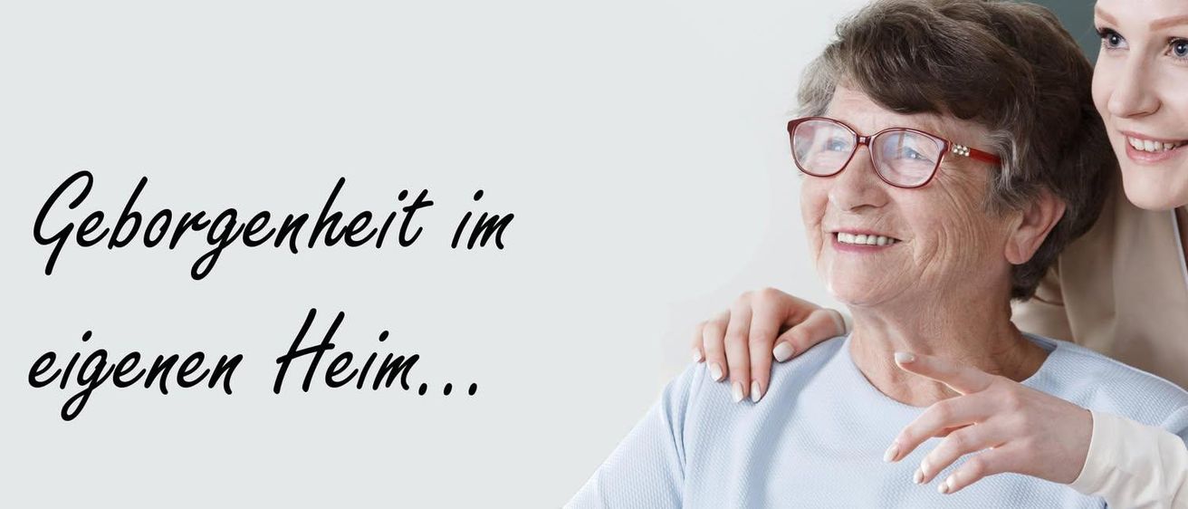 Eine ältere Frau mit Brille und blauem T-Shirt lächelt und zeigt auf den Text 'beit im hin...' vor weißem Hintergrund.