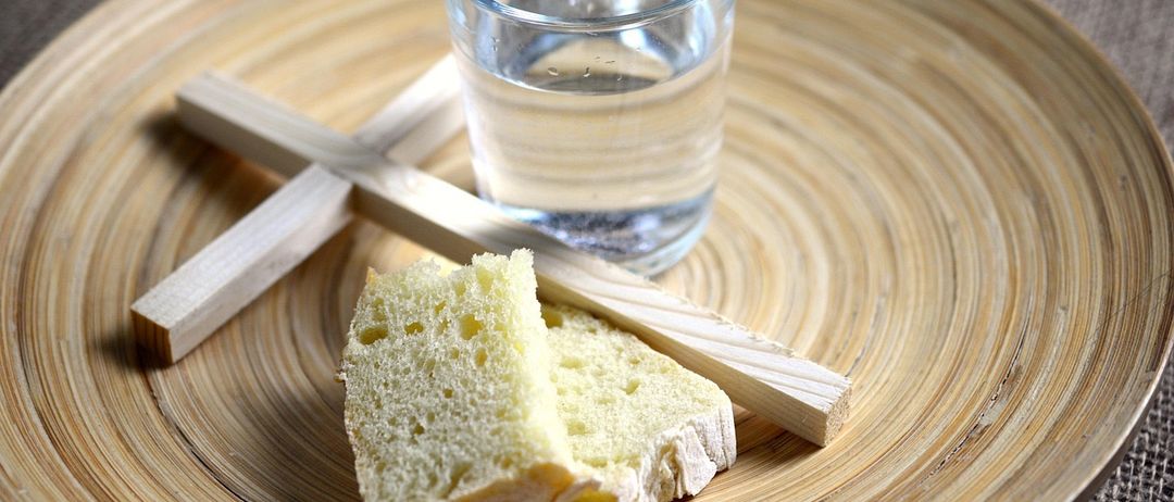 Eine Nahaufnahme eines Tellers mit zwei Stücken Brot und einem Glas Wasser.