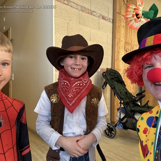 Drei Kinder in Kostümen: einer als Cowboy, ein anderes als Spiderman und ein Clown. Das Event findet am 4. März 2025 statt.