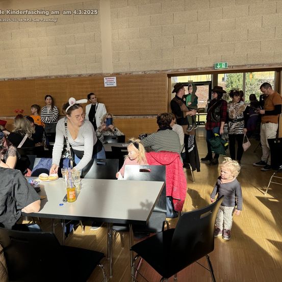 Ein Saal voller Menschen, einschließlich Erwachsener und Kinder, feiert eine Party. Die Frau steht und trägt Hasenohren. Die Kinder spielen, während die Erwachsenen ein Gespräch führen.