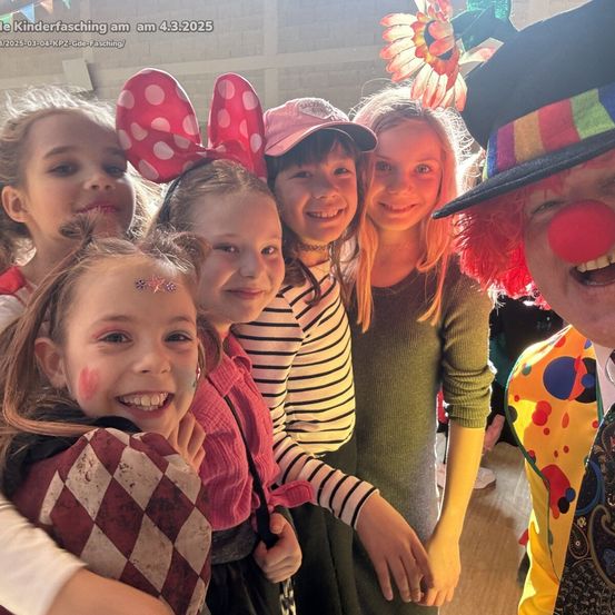 Eine Gruppe von Kindern und ein Clown posieren für ein Foto beim Kinderfasching am 4. März 2025. Die Kinder tragen verschiedene Gesichtsbemalungen und Kostüme.