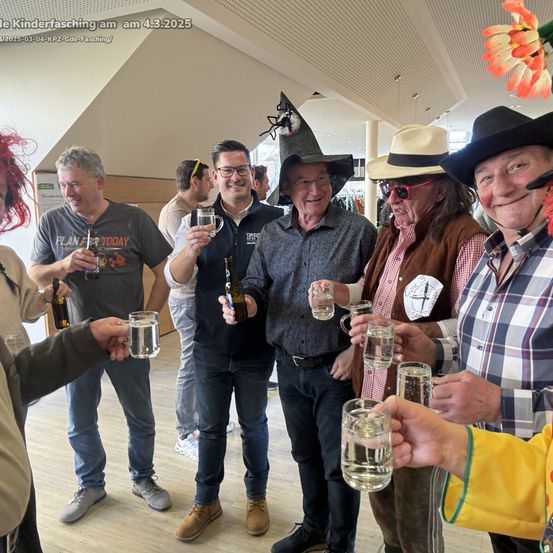 Mehrere Menschen sind in Kostümen gekleidet. Sie halten Biergläser hoch. Sie lächeln. Sie scheinen zu feiern. Das Foto wurde am 4. März 2025 aufgenommen.