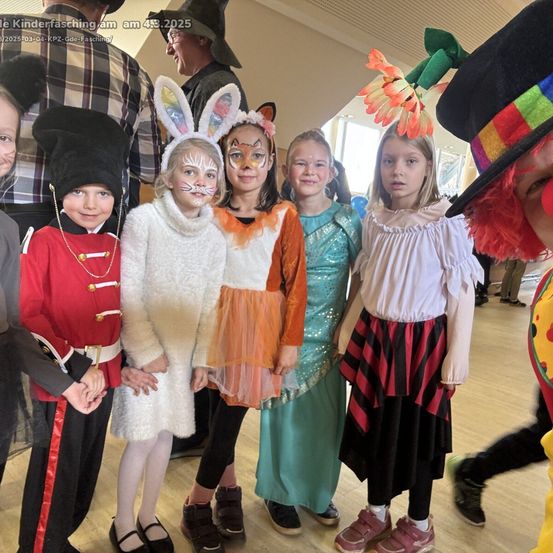 Eine Gruppe von Kindern in Kostümen steht in einem Raum zusammen, eines als Hase, ein anderes als Fuchs, ein Soldat und ein Pirat gekleidet. Ein Clown im Hintergrund.