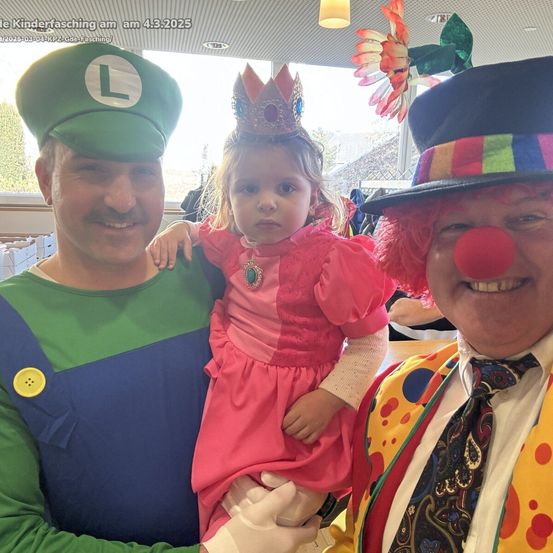 Drei Personen in Kostümen, einer in einem Mario-Outfit, ein anderer in einem Clownkostüm und ein Kind in einem Prinzessinnenkleid, posieren für ein Foto.