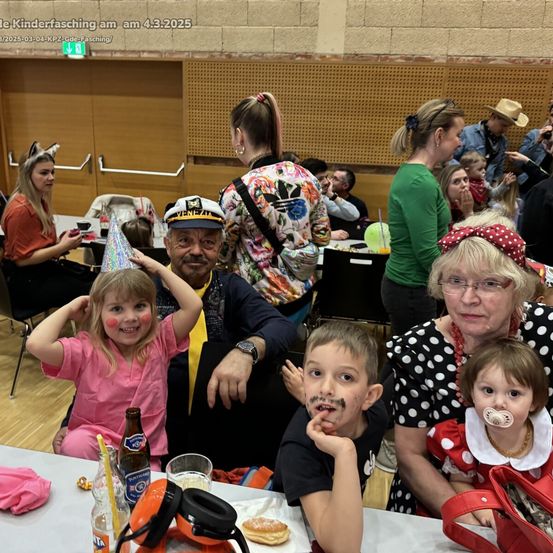 Eine Familie von Erwachsenen und Kindern in Kostümen auf einer Party, mit einem Mann in einer Matrosenmütze und einer Frau in einem Tupfenkleid. Sie sitzen um einen Tisch mit Getränken und Essen.