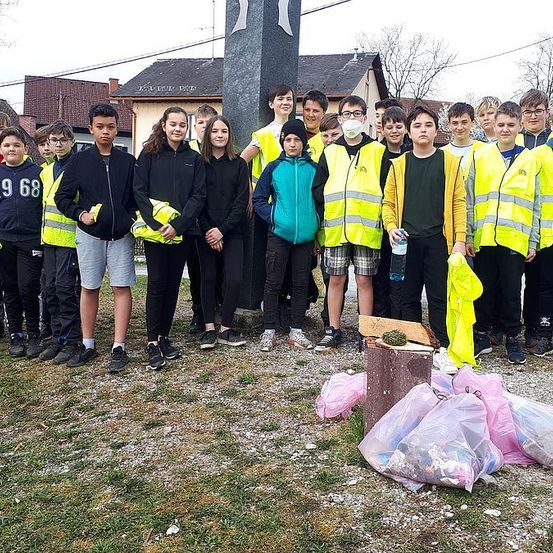 Eine Gruppe junger Menschen in Warnwesten posiert für ein Foto mit Müllsäcken vor ihnen.