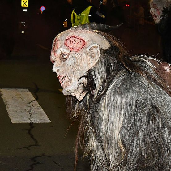 Eine Person in einem Monsterkostüm mit einer blutigen Wunde auf der Stirn läuft nachts auf der Straße.