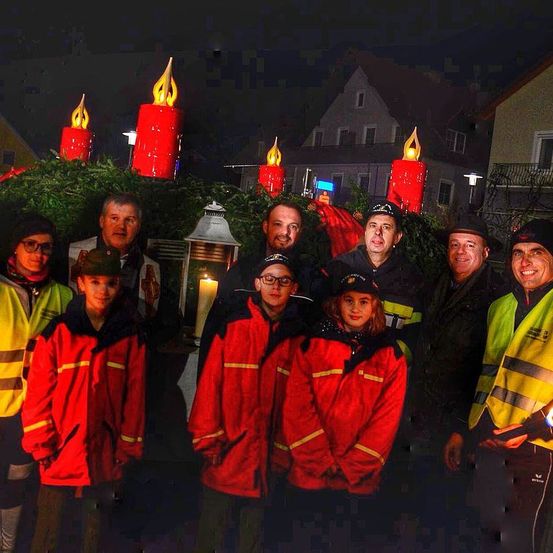 Eine Gruppe Feuerwehrleute posiert für ein Foto vor einem Haus mit Weihnachtsdekoration bei Nacht.