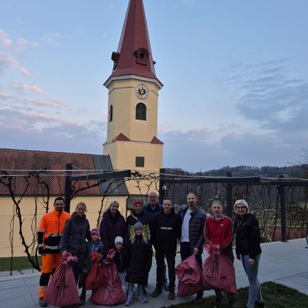 Eine Gruppe von Menschen, die rote Taschen halten, posiert für ein Foto vor einem Turm mit einer Uhr.