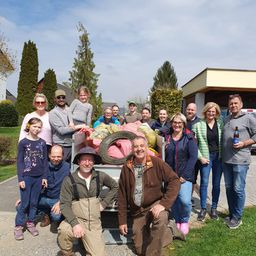 Eine Gruppe von Menschen posiert für ein Foto vor einem Haus mit einem vollgepackten Müllwagen dahinter.