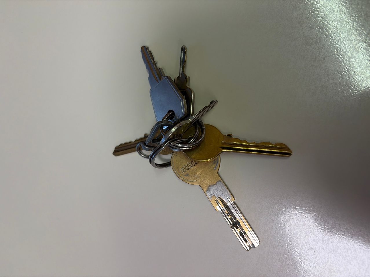 A collection of keys with different shapes and sizes, including one labeled 'DOR', are arranged on a white surface.