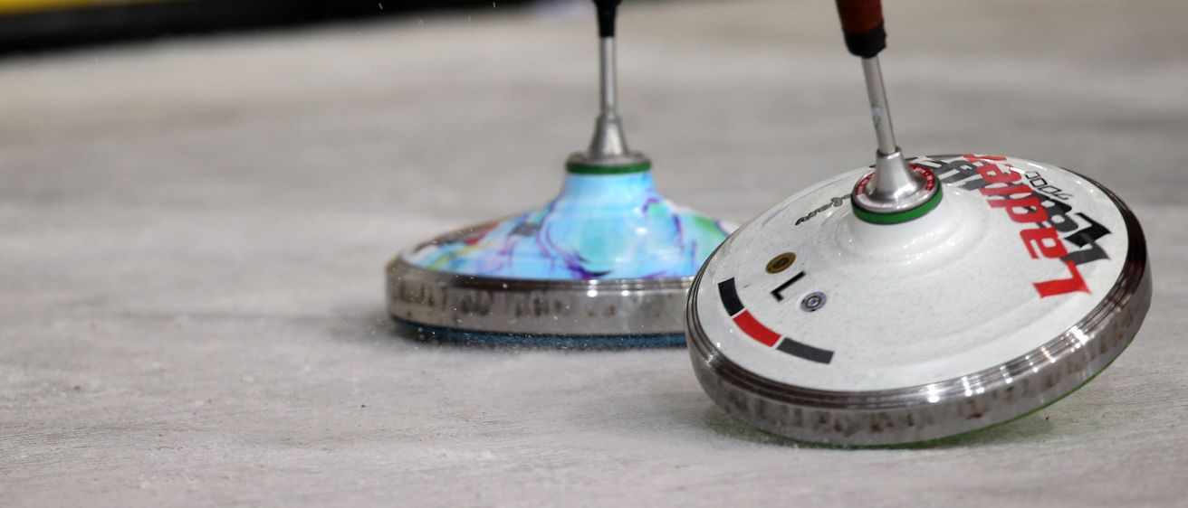 Zwei Spinner-Spielzeuge auf einer weißen Oberfläche, eines mit blauem Griff und das andere mit braunem Griff. Der Hintergrund ist unscharf.