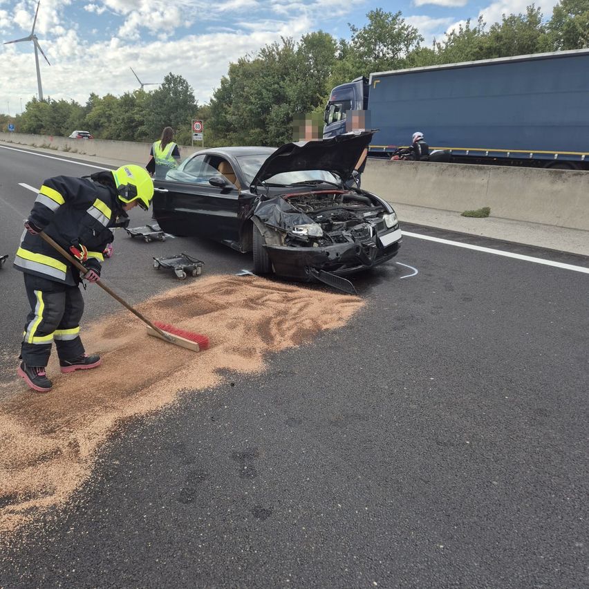 Ein Feuerwehrmann fegt Trümmer von einem verunglückten Auto am Straßenrand weg.