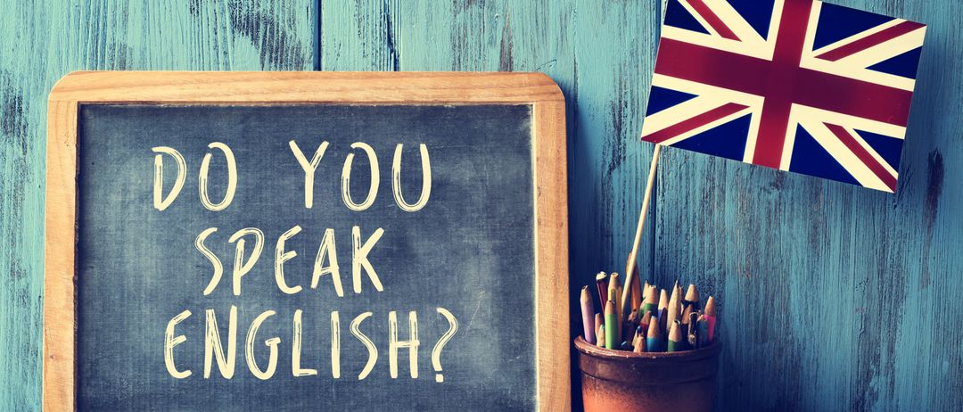 Ein Tafel mit der Frage 'Sprechen Sie Englisch?' steht neben einem Stifttopf und einer britischen Flagge.
