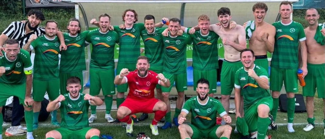 Eine Fußballmannschaft posiert für ein Foto auf dem Feld, wobei einige Spieler rote und andere grüne Trikots tragen.