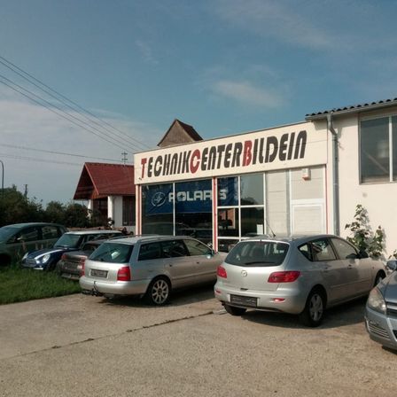 Ein Gebäude mit dem Schild Technik Center Bildein, vor dem mehrere Autos geparkt sind.