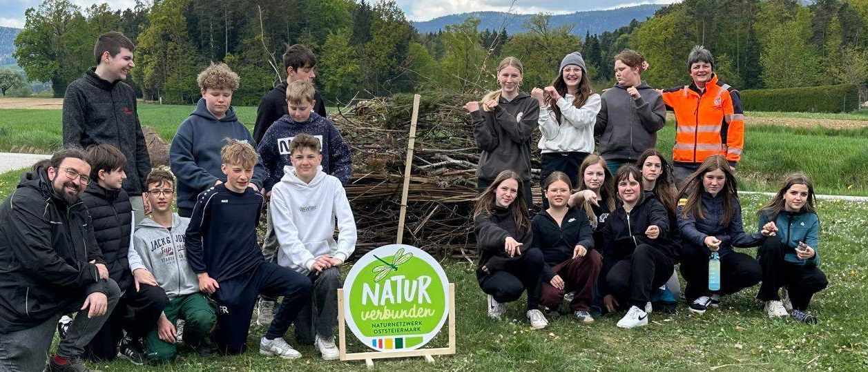 Eine Gruppe von Menschen, einschließlich Kindern, posiert für ein Foto auf einem Feld mit einem Schild für Nature Unbound.