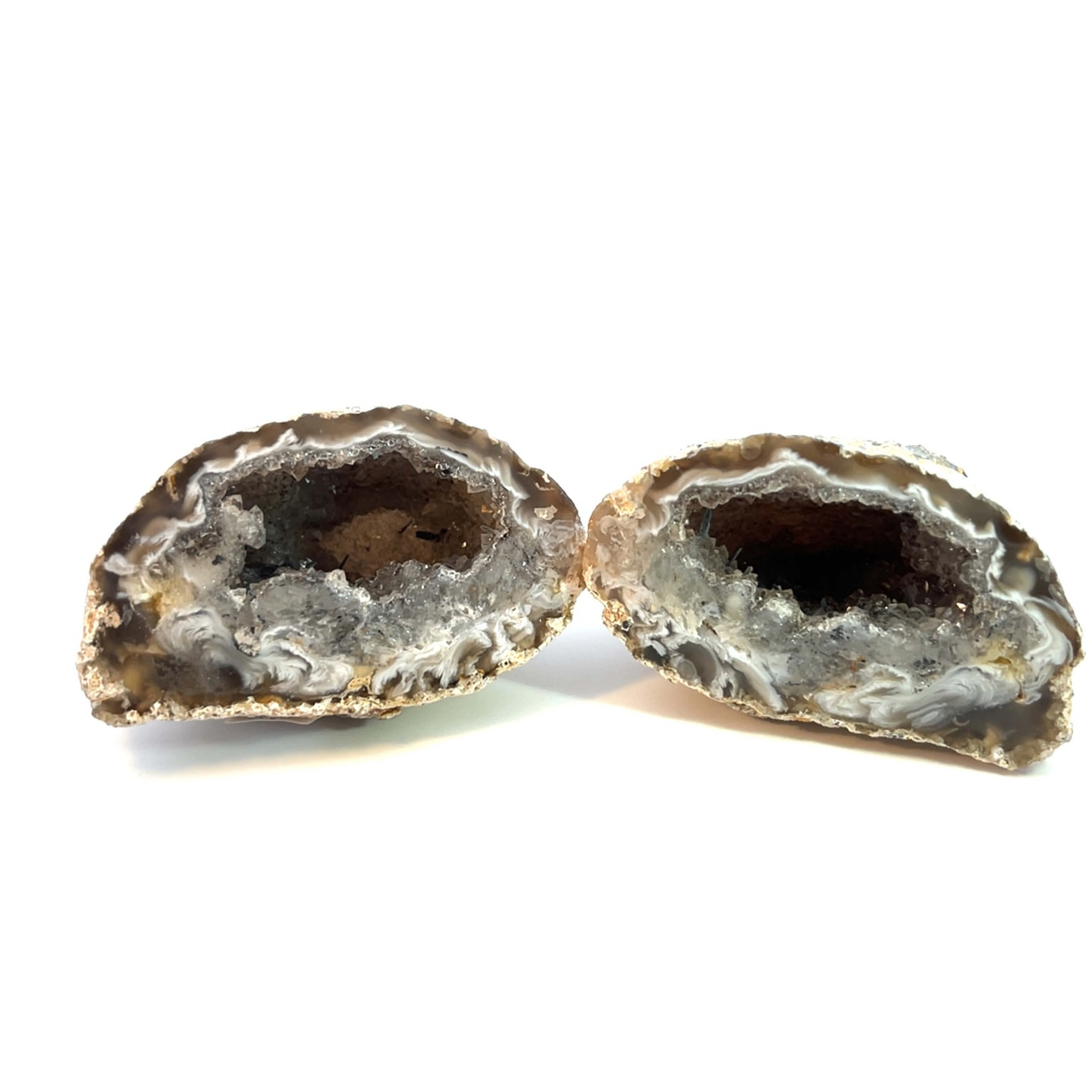Zwei Hälften eines Geods, jeweils mit einer großen Öffnung und rauer Textur, werden auf einem weißen Hintergrund gezeigt.