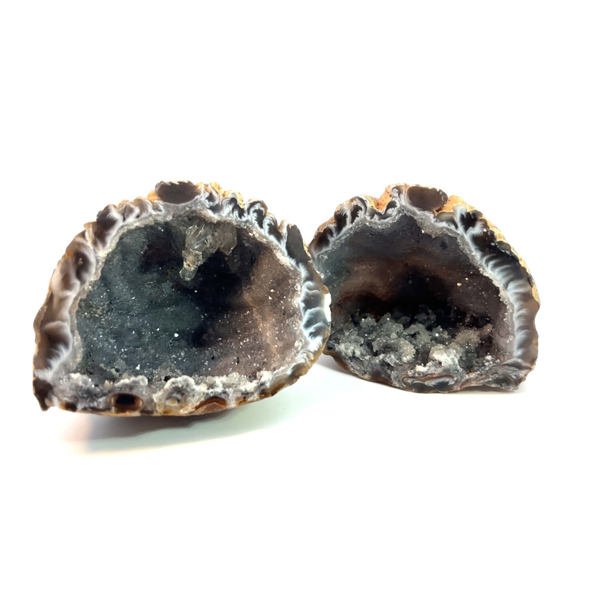 Zwei Hälften eines Geods werden gezeigt und zeigen ihre inneren Kristallstrukturen. Die äußeren Schalen sind rau und braun, mit weißen und grauen Kristallen im Inneren.