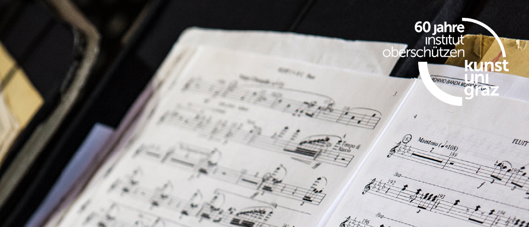 Geöffnetes Musikblatt mit Musiknoten. Der Text lautet: 'Dienstag, 25.11.2024 19:30. Podiumskonzert mit Studierenden des Instituts der Kunstuniversität Graz.' Ein rosa Kreis mit den Worten 'Eintritt freie Spende'.