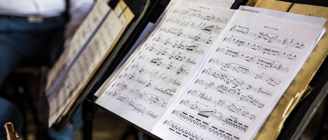 Ein offenes Notenblatt auf einem Notenständer, mit mehreren Zeilen musikalischer Noten und Symbole.