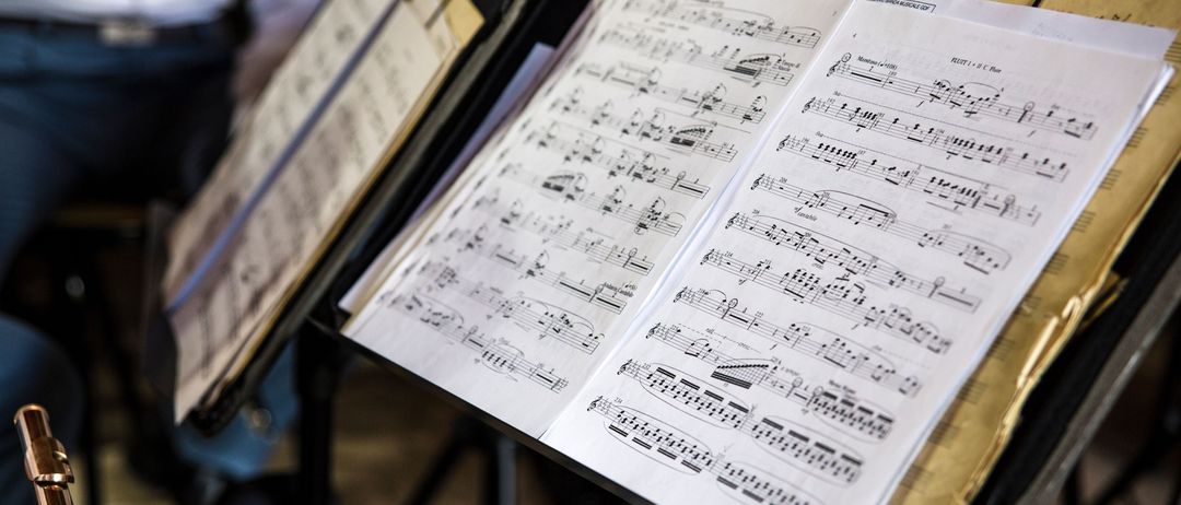Ein offenes Notenblatt mit Musiknoten auf einem Notenständer, mit verschwommenem Hintergrund.