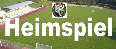 Ein Luftbild eines Fußballfeldes mit dem Wort 'Heimspiel' in Weiß auf grünem Hintergrund. Das Feld ist von einer roten Laufbahn umgeben und hat in der Mitte ein Logo eines Fußballvereins.