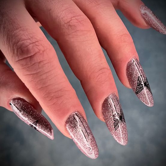 Ein Nahaufnahme einer Hand, die Nägel mit aufwendigen Schmetterlingsdesigns in rosa Glitzer zeigt. Die Nägel sind präzise poliert.