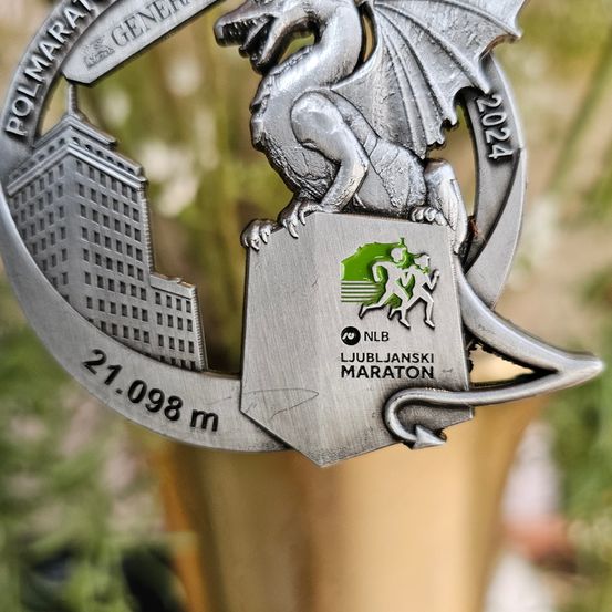 Eine silberne Medaille für den Ljubljana Marathon im Jahr 2024 mit einem Drachen und der Distanz von 21,098 Metern.