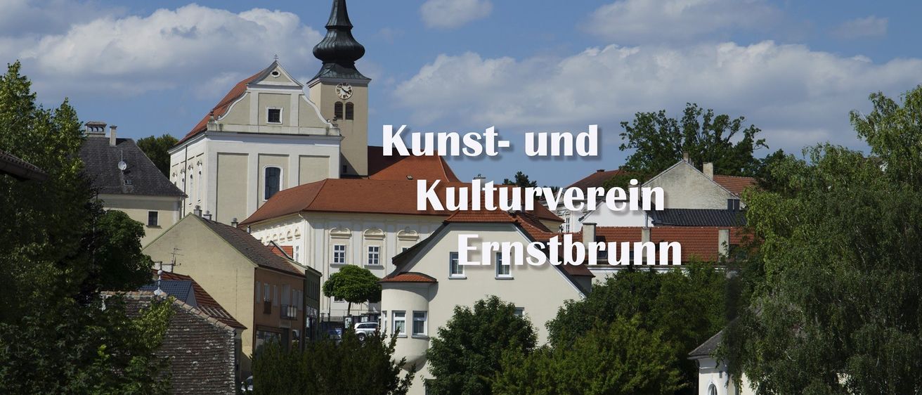 Ein Gebäude mit einem Glockenturm und einem roten Dach trägt die Aufschrift Kunst- und Kulturverein Ernstbrunn. Das Gebäude ist von Bäumen und anderen Gebäuden umgeben.