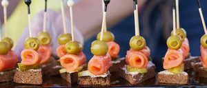 Eine Nahaufnahme von Canapes mit Lachs und Oliven auf Stöcken auf einem Tablett.