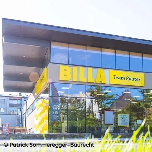 Die Vorderseite eines BILLA-Supermarkts mit gelben Luftballons und einem Schild, auf dem steht Team Rauter.