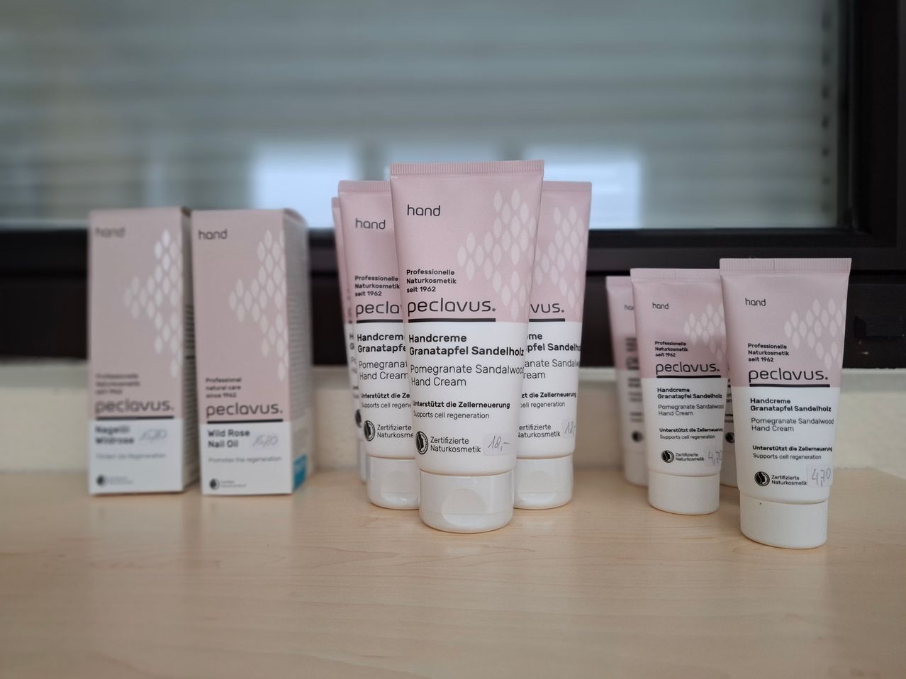 Mehrere Tuben Handcreme mit Granatapfelduft sind auf einem Holztisch angeordnet. Sie sind mit ihrer Marke und Zutaten beschriftet.