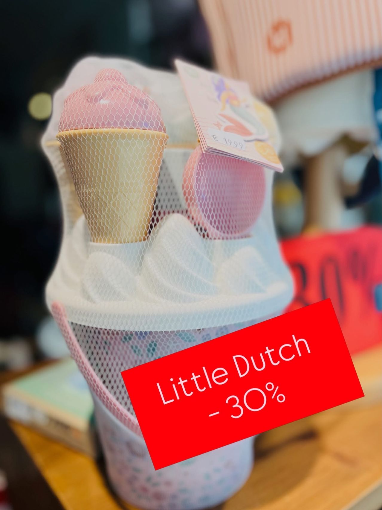 Ein Nahaufnahme eines Netzbeutels mit zwei Eistüten darin, eine rosa und eine gelbe, mit einem roten Schild darunter, das 'Little Dutch -30%' steht.