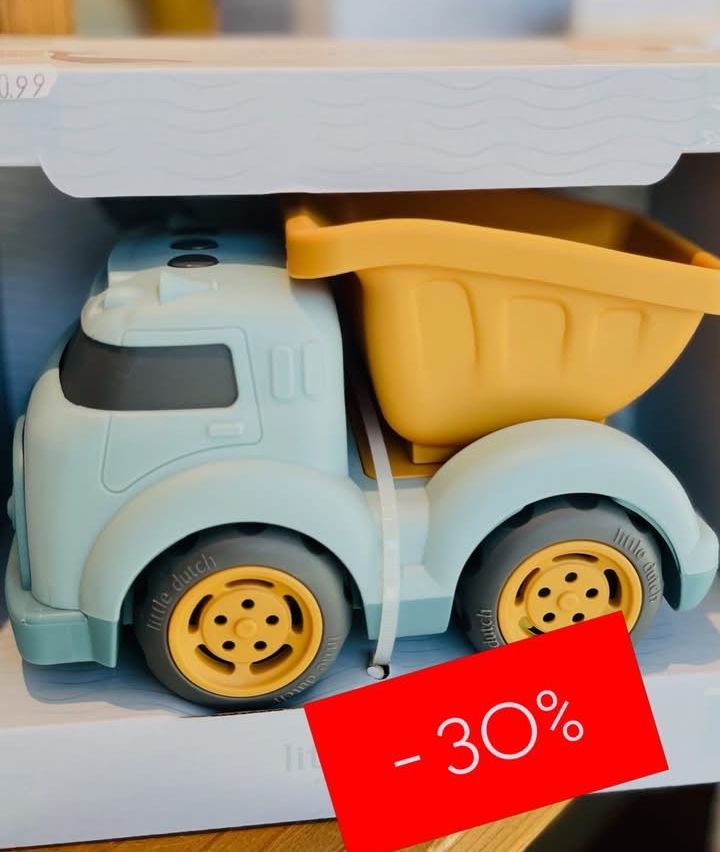 Ein blauer und gelber Spielzeuglastwagen mit einem gelben Eimer oben, gekennzeichnet mit 'Little Dutch', ausgestellt auf einem weißen Regal mit einem roten Schild, das einen 30%igen Rabatt anzeigt.